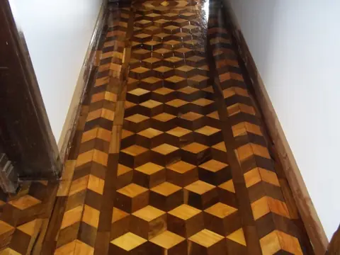 Corredor com piso de tacos em padrão geométrico